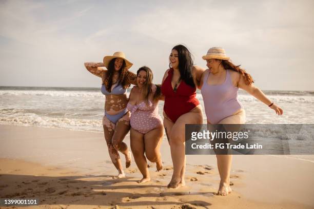 junge freundinnen, die spaß am strand haben - body positivity stock-fotos und bilder