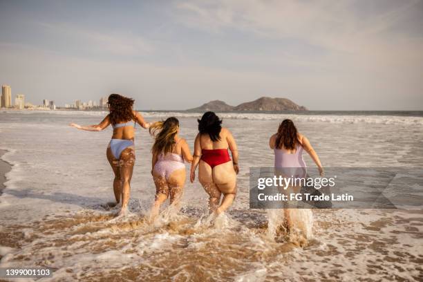 jovens amigas andando e se divertindo na praia - celulite aspecto da epiderme - fotografias e filmes do acervo