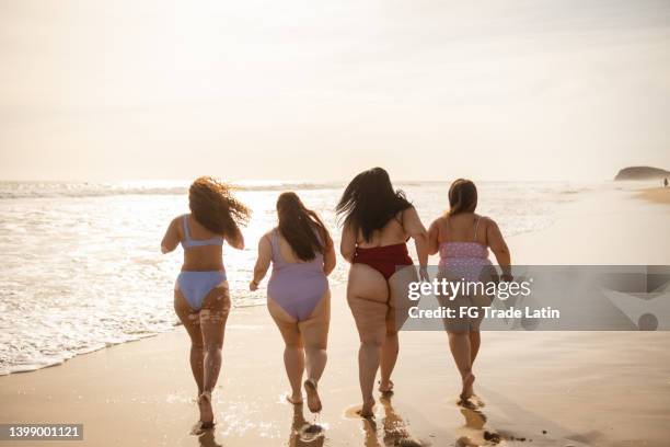 young woman friends running and having fun on the beach - chesty love stock pictures, royalty-free photos & images