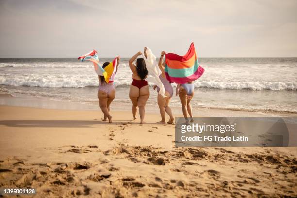 amici che tengono gli asciugamani sulla spiaggia - chubby foto e immagini stock