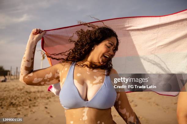 young woman holding a towel on the beach - body positive stockfoto's en -beelden