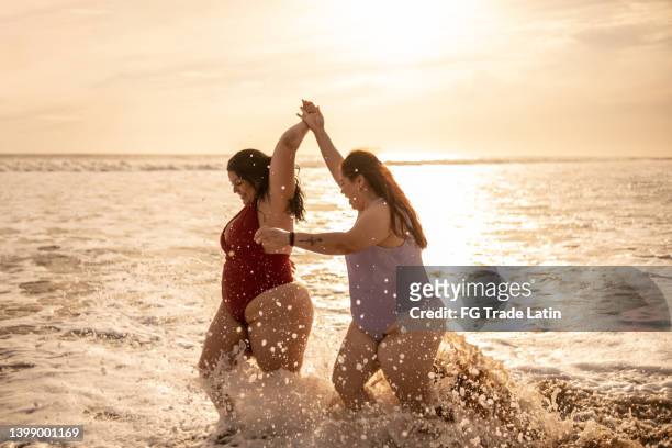 young woman friends walking on the beach - beautiful voluptuous women stock pictures, royalty-free photos & images