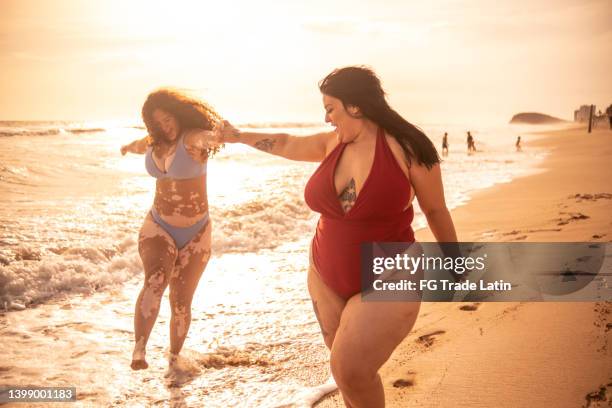 young woman friends walking on the beach - women in bathing suits stock pictures, royalty-free photos & images