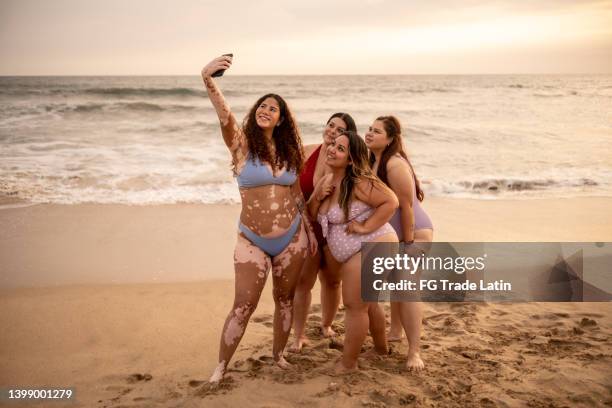 freunde, die ein selfie mit dem handy am strand machen - dicke frauen am strand stock-fotos und bilder