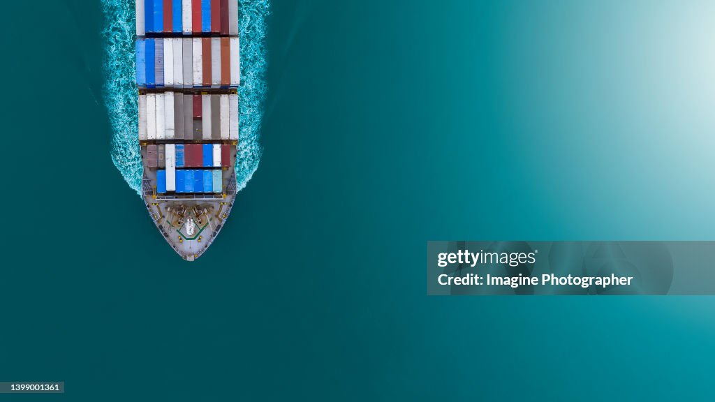Aerial top view, Large container ship ( Container ship prow ) sailing hi- speed in the blue sea. About the business of import, export, logistics and international shipping by container ships.