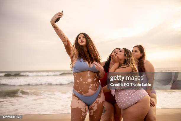 amigos tomándose un selfie usando el teléfono móvil en la playa - preocupación por el cuerpo fotografías e imágenes de stock