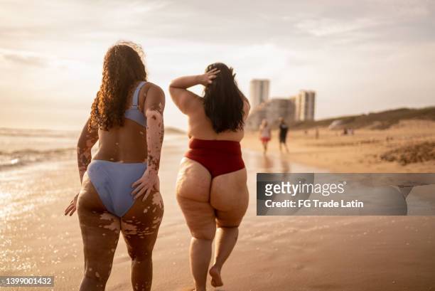 rear view of friends walking in the beach - swimwear stock pictures, royalty-free photos & images