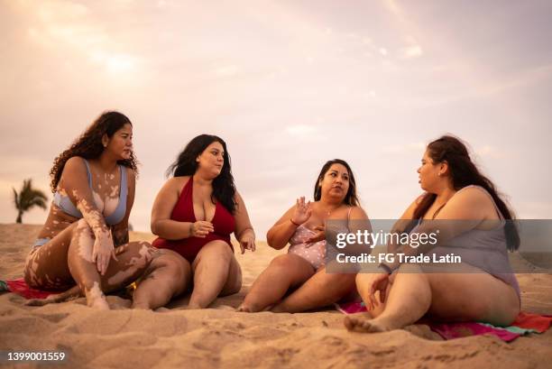 young women talking on the beach - latin beauty stockfoto's en -beelden