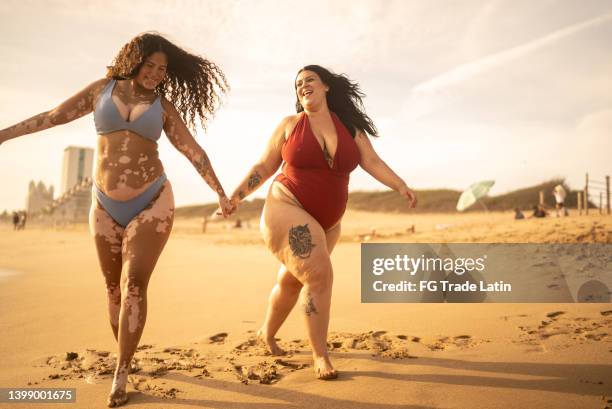friends holding hands walking in the beach - voluptuous stock pictures, royalty-free photos & images