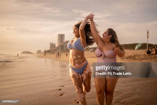 freunde, die händchen halten, gehen am strand spazieren - dicke frauen am strand stock-fotos und bilder