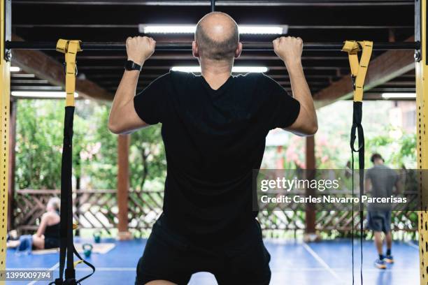 back of a man doing pull-ups in a gymnasium - skinny stock pictures, royalty-free photos & images