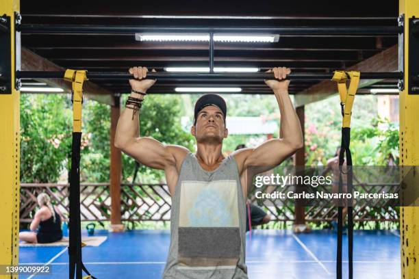 strong man holding on to a bar about to do pull-ups in a gym - bar man t shirt ストックフォトと画像