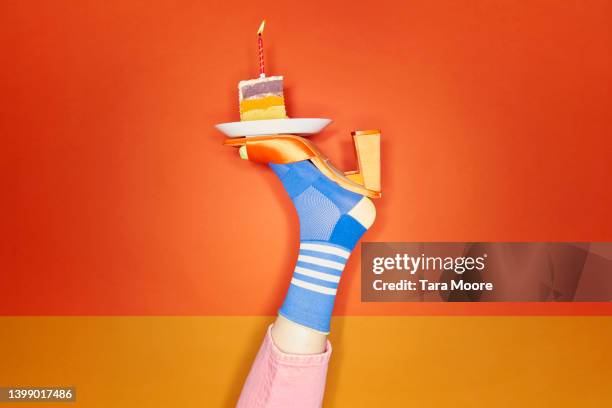 vibrant foot balancing slice of birthday cake - crazy party stockfoto's en -beelden