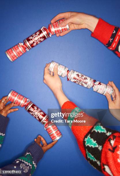 three people holding christmas crackers - smällkaramell bildbanksfoton och bilder