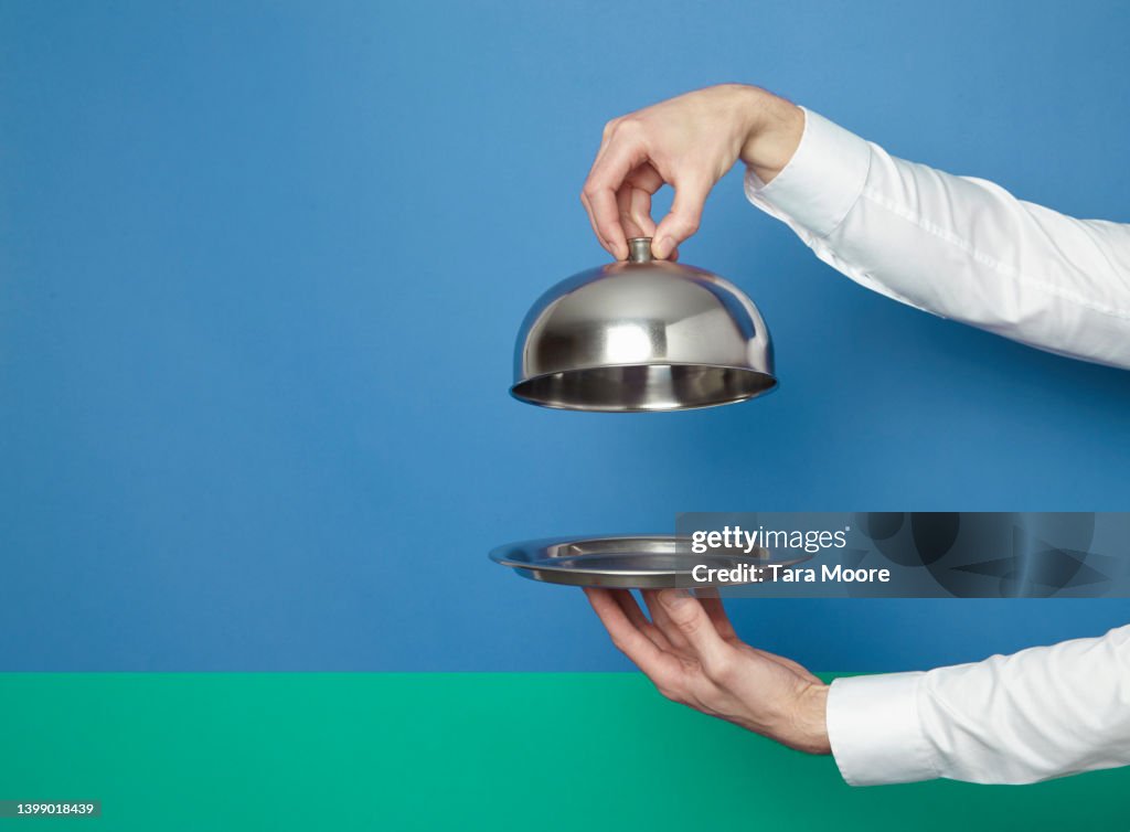 Hands holding silver tray and lid