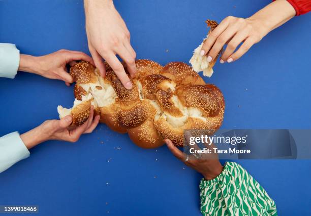 hands reaching for bread - challah stock-fotos und bilder