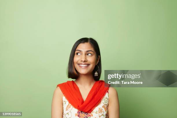 south asian woman looking to side against green background - seitenblick stock-fotos und bilder