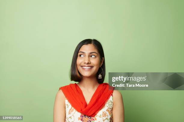 south asian woman looking to side against green background - asian man smiling stock-fotos und bilder