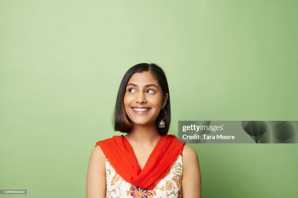 South asian woman looking to side against green background