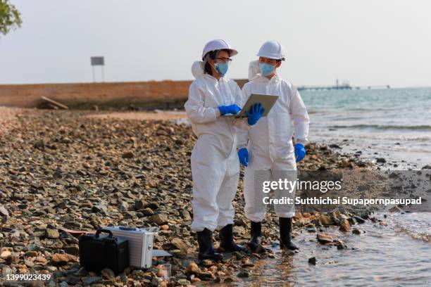 two biology researcher examining water at the industry estate. - ecologist stock pictures, royalty-free photos & images