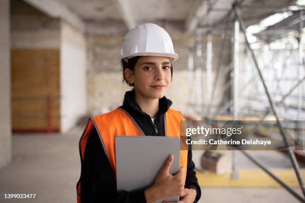 portrait of female architect holding digital tablet while examining construction site - worker with hard hat stock pictures, royalty-free photos & images