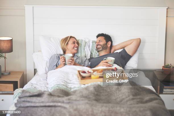 ein paar, das zu hause im bett frühstückt. ein glücklicher, reifer mann und eine verliebte frau, die sich morgens im schlafzimmer entspannen und eine köstliche mahlzeit essen - breakfast in bed tray stock-fotos und bilder