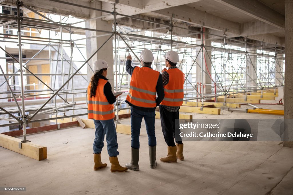 Three workers (architects, engineers) examining building site