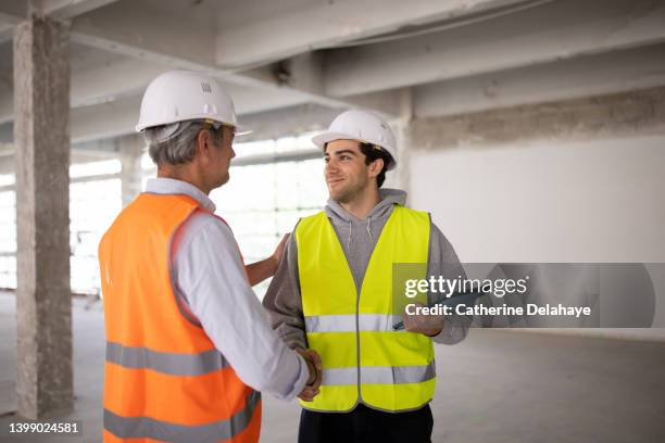 two co-workers shaking hands as they visiting a building site - confident young man at work stock pictures, royalty-free photos & images