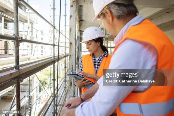 portrait of female architect holding digital tablet while examining construction site with a co-worker - foundations gender equality discussion foto e immagini stock