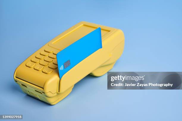 yellow credit card pos terminal on blue background - digital payment imagens e fotografias de stock