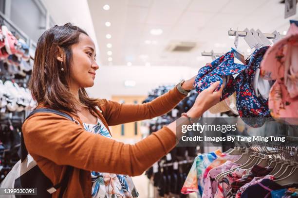 young pretty asian woman shopping for swimwear in clothing store joyfully - swimwear store stock pictures, royalty-free photos & images