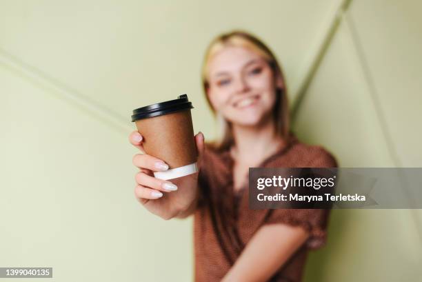 beautiful blonde girl with a cardboard cup. woman with coffee. woman with tea. cappuccino, latte, espresso, americano. lifestyle. drink. coffee house. - takeaway coffee stockfoto's en -beelden