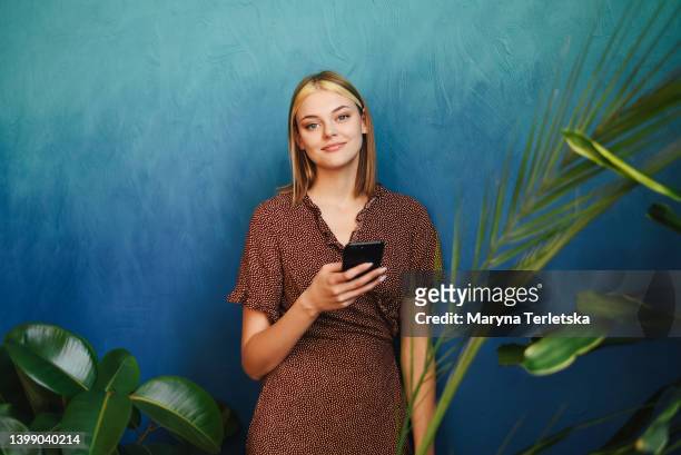 a beautiful girl stands with a smartphone in her hands. telephone. internet. work searches. remote or remote work. work from home. communication in social networks. modern life style. - hair growth stock pictures, royalty-free photos & images