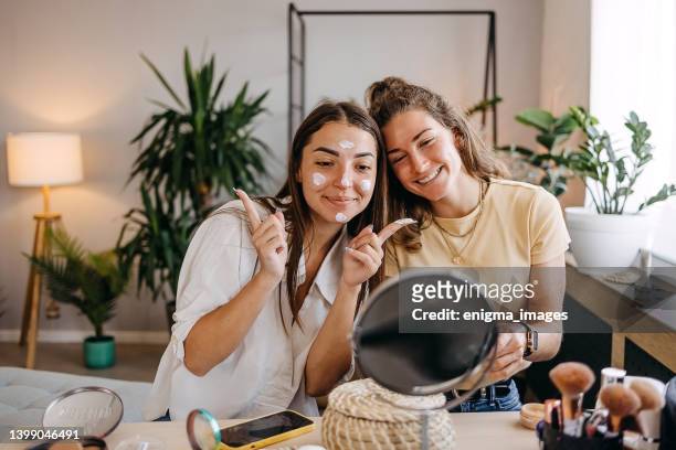 dos chicas felices aplicando maquillaje en casa - beauty treatment fotografías e imágenes de stock
