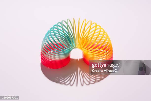 colorful coil toy arch bending on pink background - curled up - fotografias e filmes do acervo