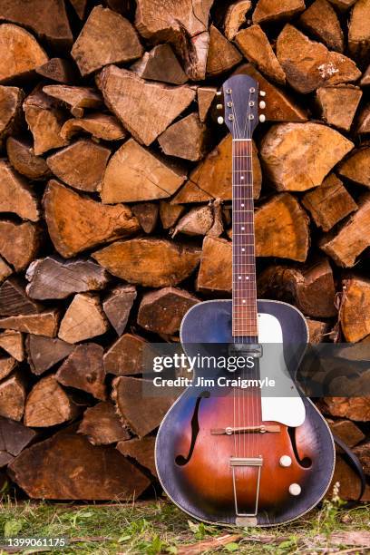 woodshedding, guitar leaning against a stack of firewood - jim craigmyle guitar stock pictures, royalty-free photos & images