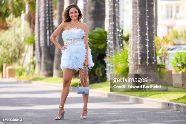 Patricia Gloria Contreras wears a pastel blue fluffy off-shoulder low-neck mini dress with a middle part made of tulle fabric, a blue bag, silver...