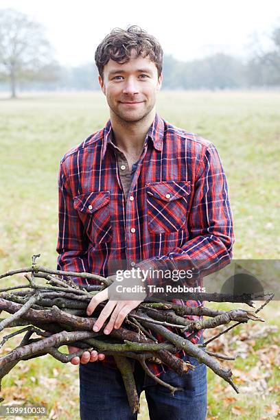 young man holding firewood. - firewood stock-fotos und bilder