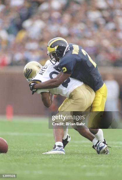 Defensive back Charles Woodson of the Michigan Wolverines tackles flanker Derek Ayers of the UCLA Bruins during a game at Michigan Stadium in Ann...