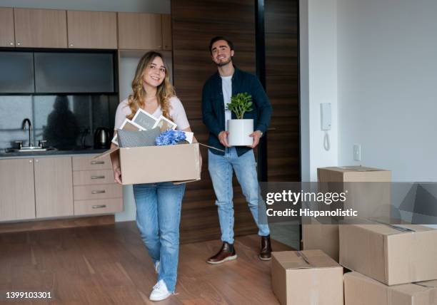 happy couple moving to their new house and carrying boxes - civilian stock pictures, royalty-free photos & images