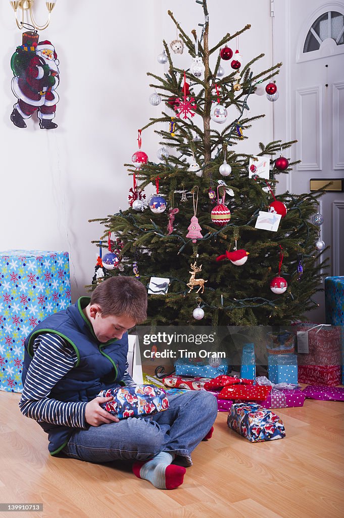 Boy opening presents under Christmas tree