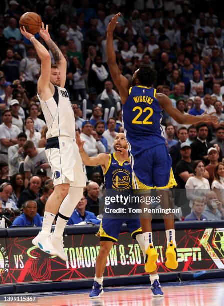 Luka Doncic of the Dallas Mavericks passes the ball inbounds against Andrew Wiggins and Stephen Curry of the Golden State Warriors during the fourth...