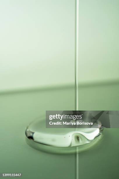 a drop of oil, serum or other cosmetic product on a green background. - facial cleanser stockfoto's en -beelden