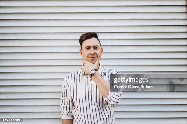 young man in striped shirt holding hand on chin. - portrait solid stock pictures, royalty-free photos & images