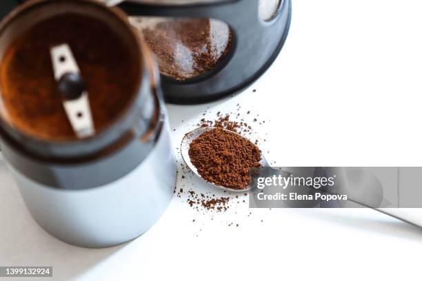 coffee plunger and coffee grinder with spoon full of  organic arabica - coffee grinder stock-fotos und bilder