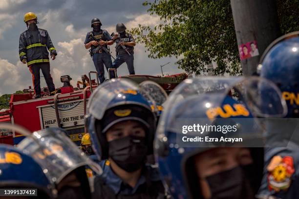 Heavily armed police officers stand guard as anti-Marcos activists take part in a protest against election results at the Commission on Human Rights...