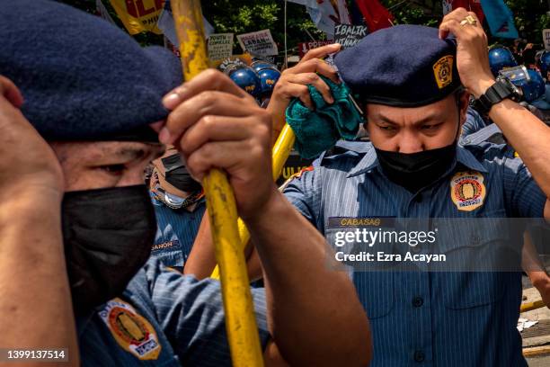 Riot police officers take position as anti-Marcos activists take part in a protest against election results at the Commission on Human Rights office...