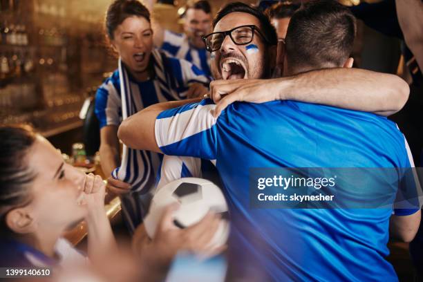 joyful soccer fans celebrating the victory of their team in a bar. - fans embracing stock pictures, royalty-free photos & images