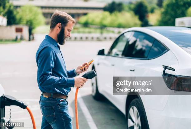 man charging electric car - elektrische auto stockfoto's en -beelden