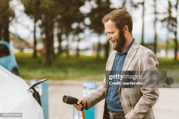 mann elektroauto aufladen - elektro auto stock-fotos und bilder